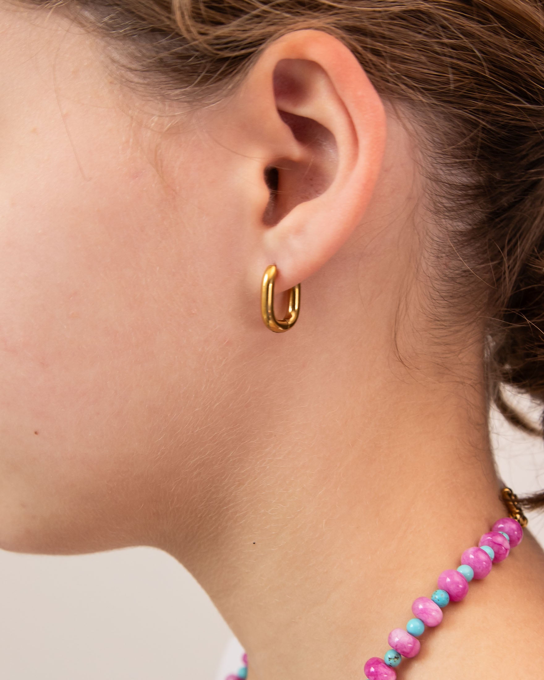 Close up picture of a gold hoop oval earring by Kaleidoscope Living.