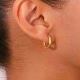 Gold hoop earring worn by a person with dark hair.