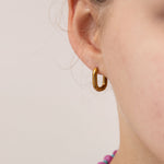 Close up of gold oval huggie worn by a girl.  