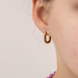 Close up of gold oval huggie worn by a girl.  