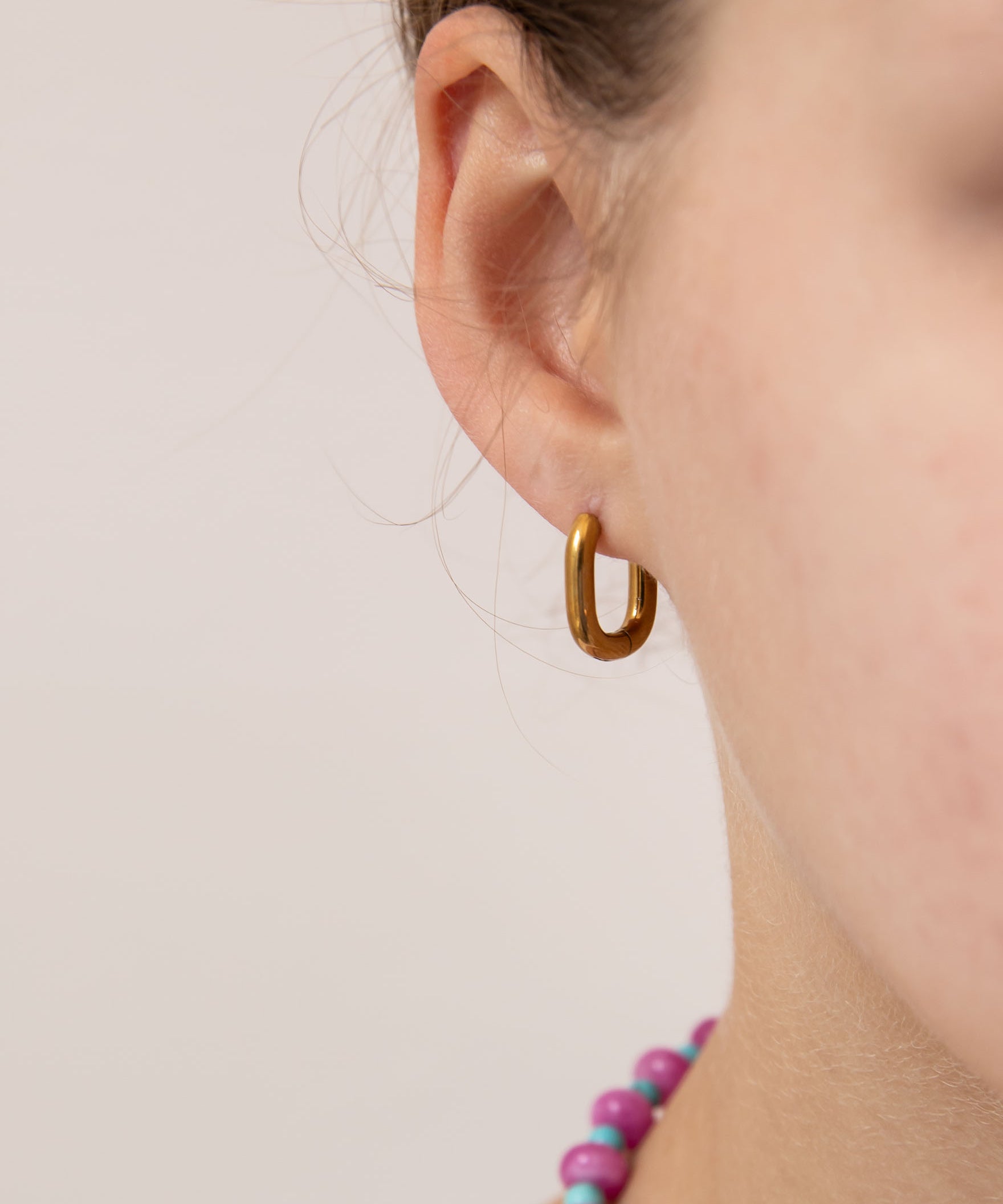 Close up of gold oval huggie worn by a girl.  