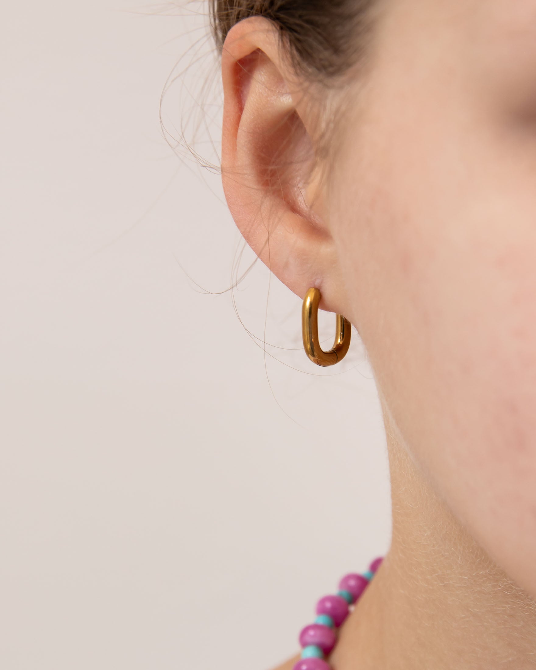 Close up of gold oval huggie worn by a girl.  