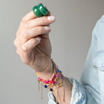 Hand holding a pair of green hoop earrings by Kaleidoscope Living.