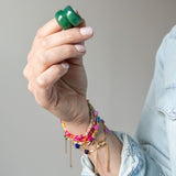 Hand holding a pair of green hoop earrings by Kaleidoscope Living.