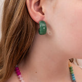 Close-up of a girl wearing a green acrylic hoop earring with colorful beads around her neck.