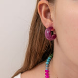 Close-up of a person wearing a purple acrylic earring by Kaleidoscope Living