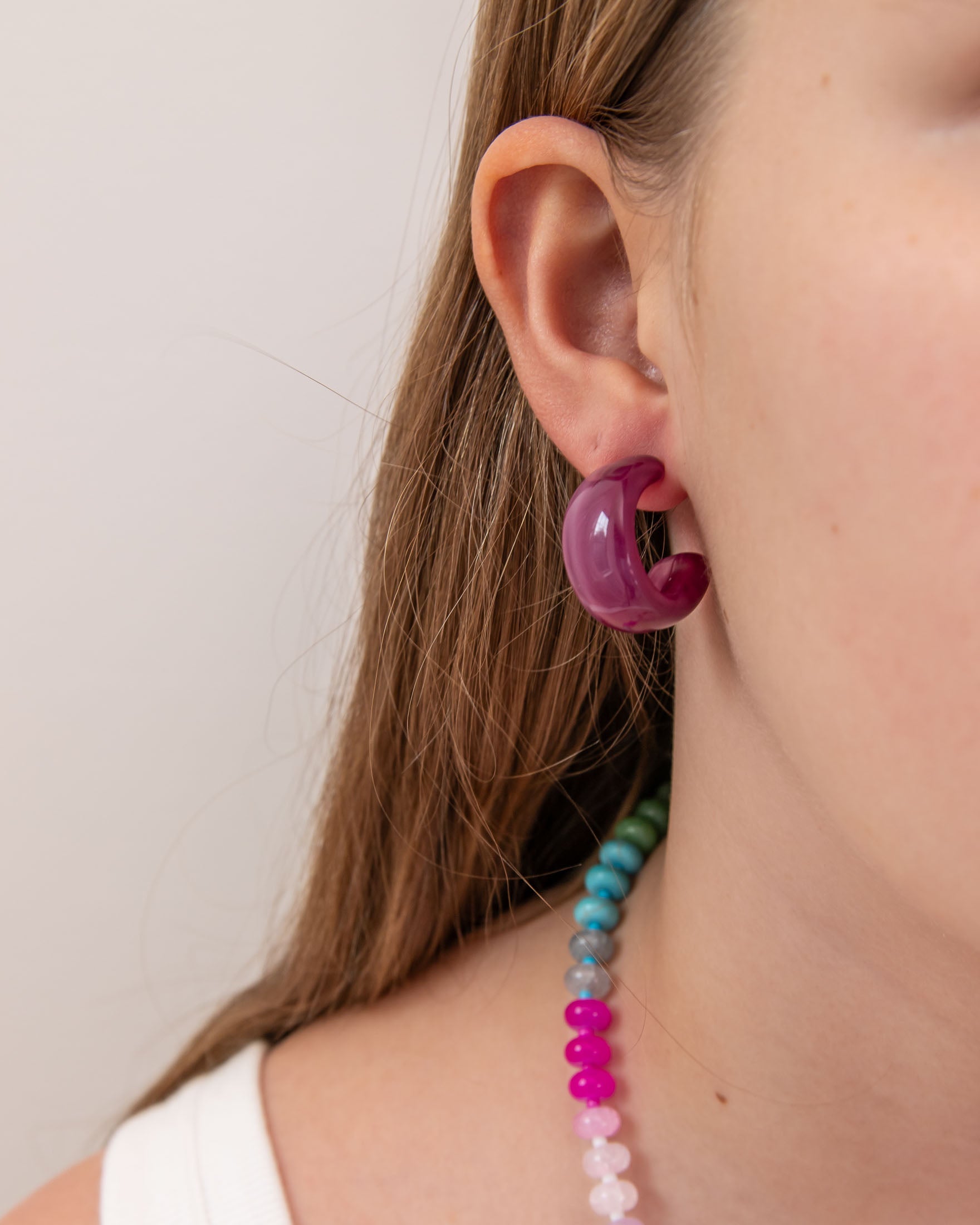 Close-up of a person wearing a purple acrylic earring by Kaleidoscope Living