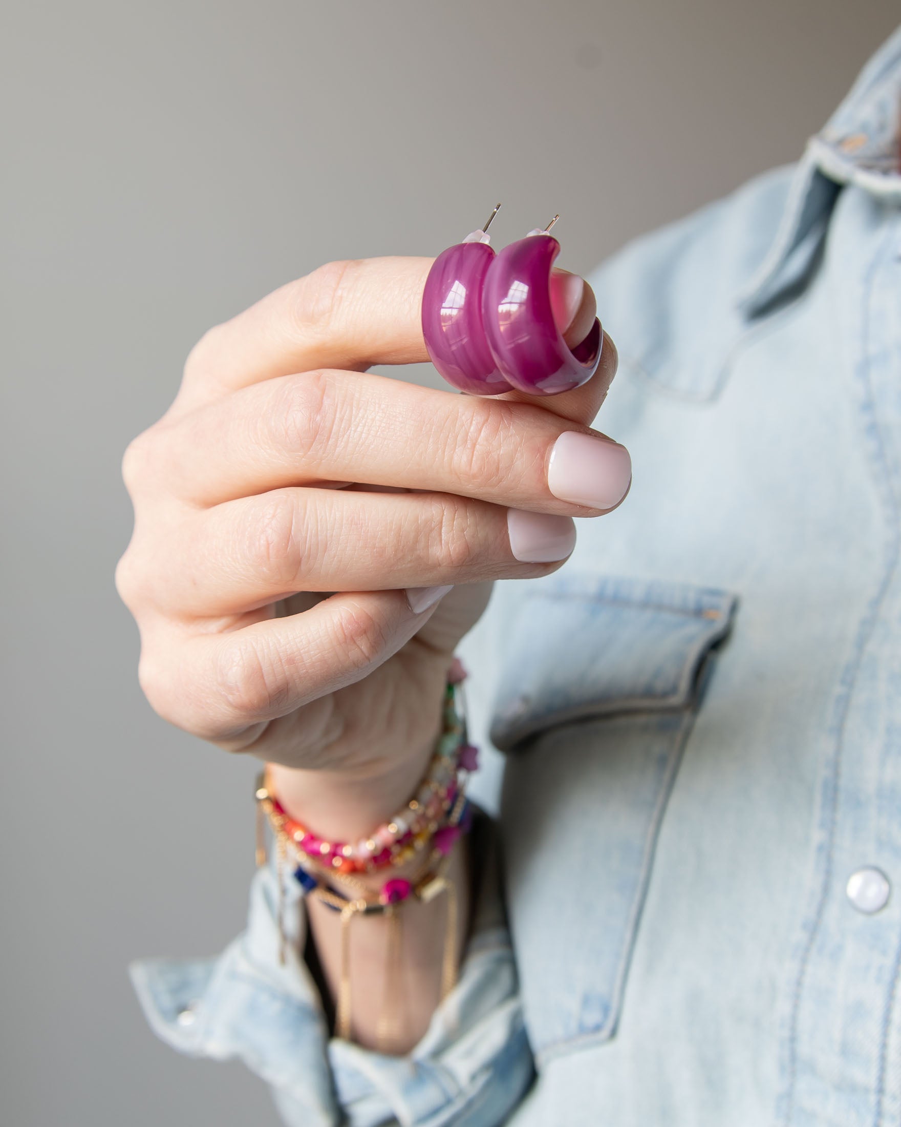 Hand holding a set of purple acrylic earrings by Kaleidoscope Living