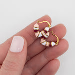 Gold, pink and red striped huggie earrings help in a hand by Kaleidoscope Living