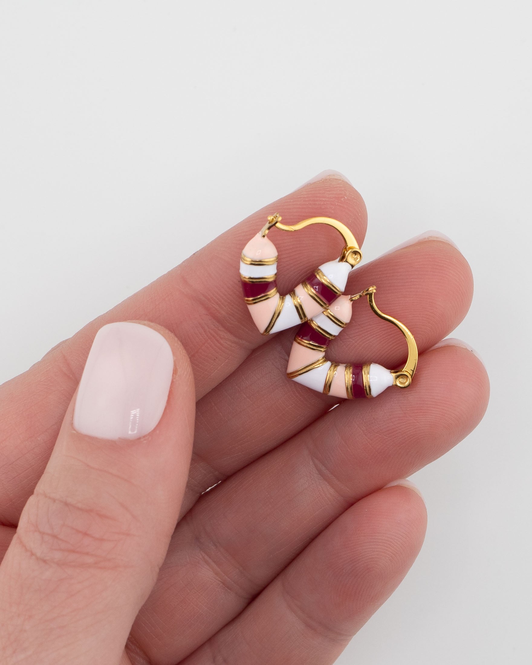 Gold, pink and red striped huggie earrings help in a hand by Kaleidoscope Living