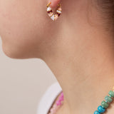 Close-up of a person wearing a pink, white and red striped huggie earring in a heart shape.