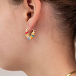 Close-up of a girl wearing colorful heart-shaped huggie earring by Kaleidoscope Living.