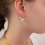 Close-up of a person wearing a colorful heart shape earring by Kaleidoscope Living