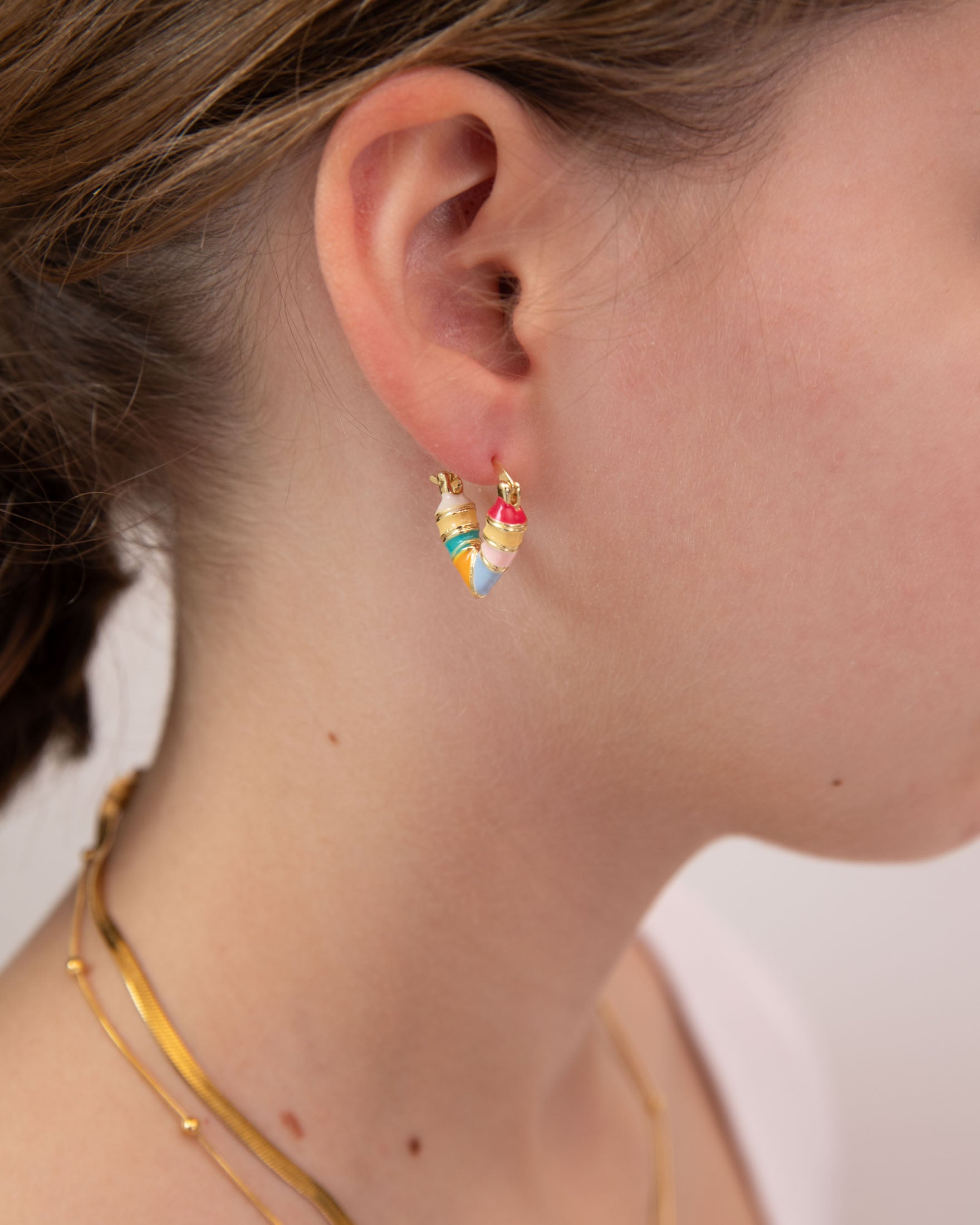 Close-up of a person wearing a colorful heart shape earring by Kaleidoscope Living