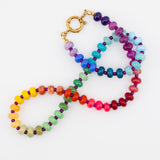 Colorful beaded necklace with gold clasp lying on a white table