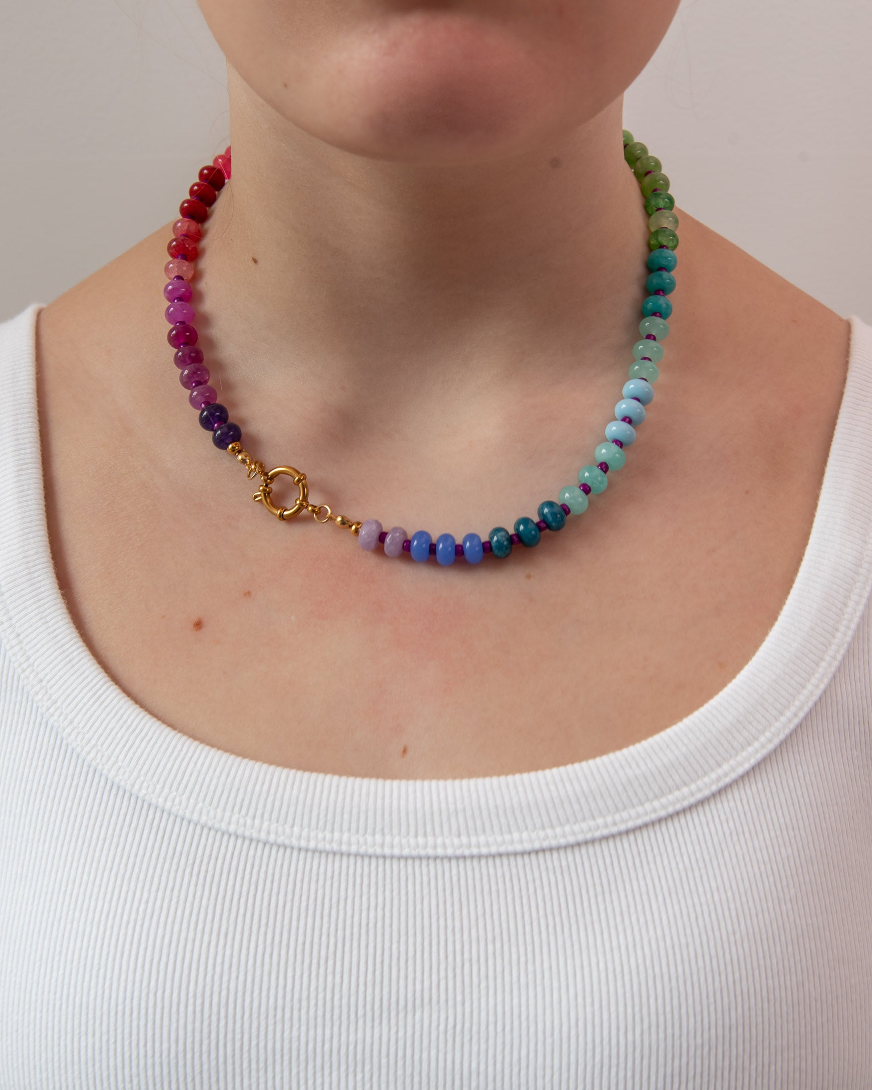 Rainbow gradient beaded necklace worn by a women showing the gold clasp worn to the side