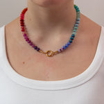 Multicolored round beaded necklace with a gold clasp worn in front 