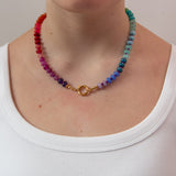 Multicolored round beaded necklace with a gold clasp worn in front 