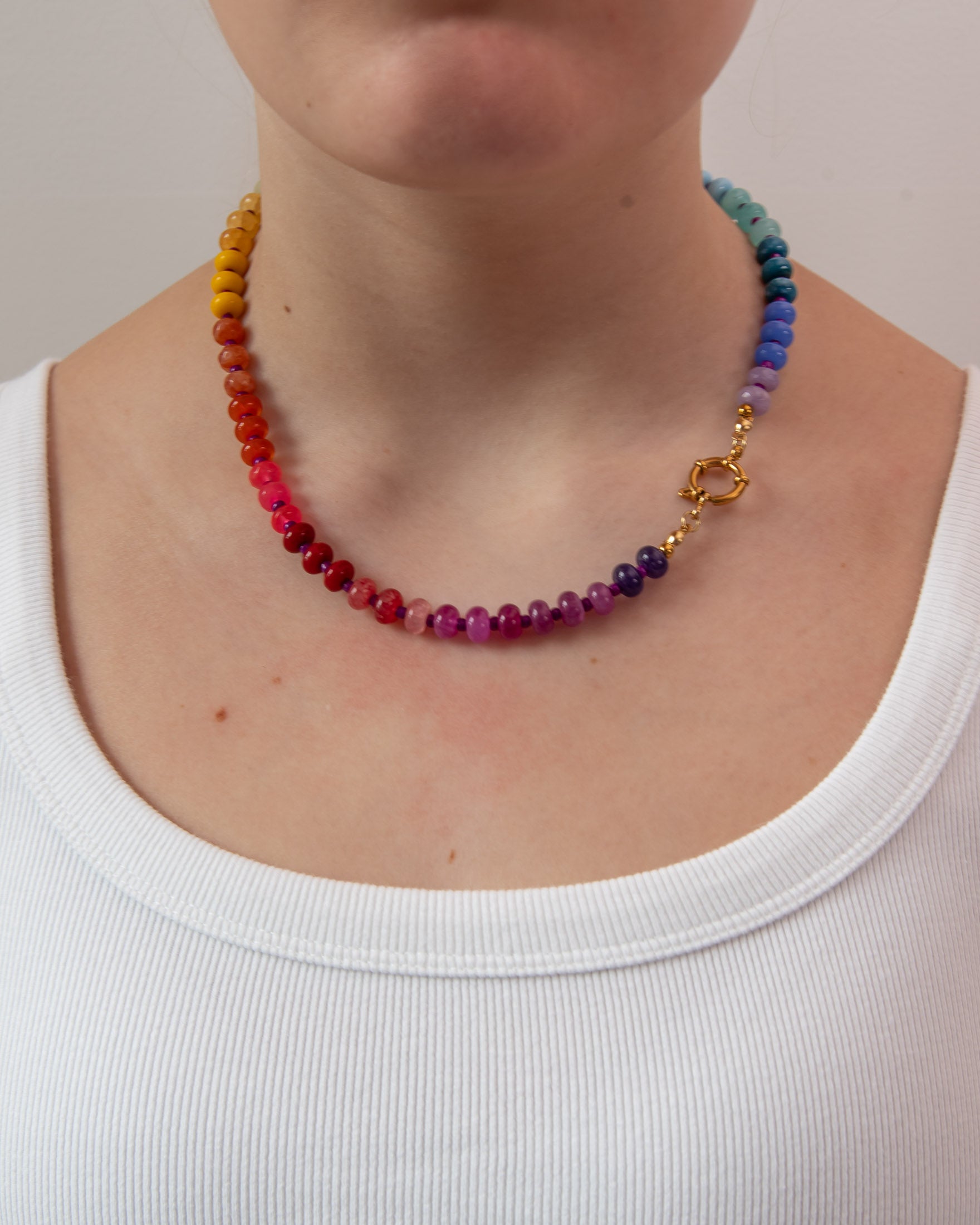 Rainbow gradient beaded necklace on a women wearing a white t-shirt showing the gold clasp to the side.