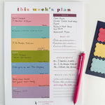 A weekly planner page from Kaleidoscope Living filled in with meals, appointments, and to-do lists, styled on a white background with a pink pen and colorful scalloped sticky notes on the side.