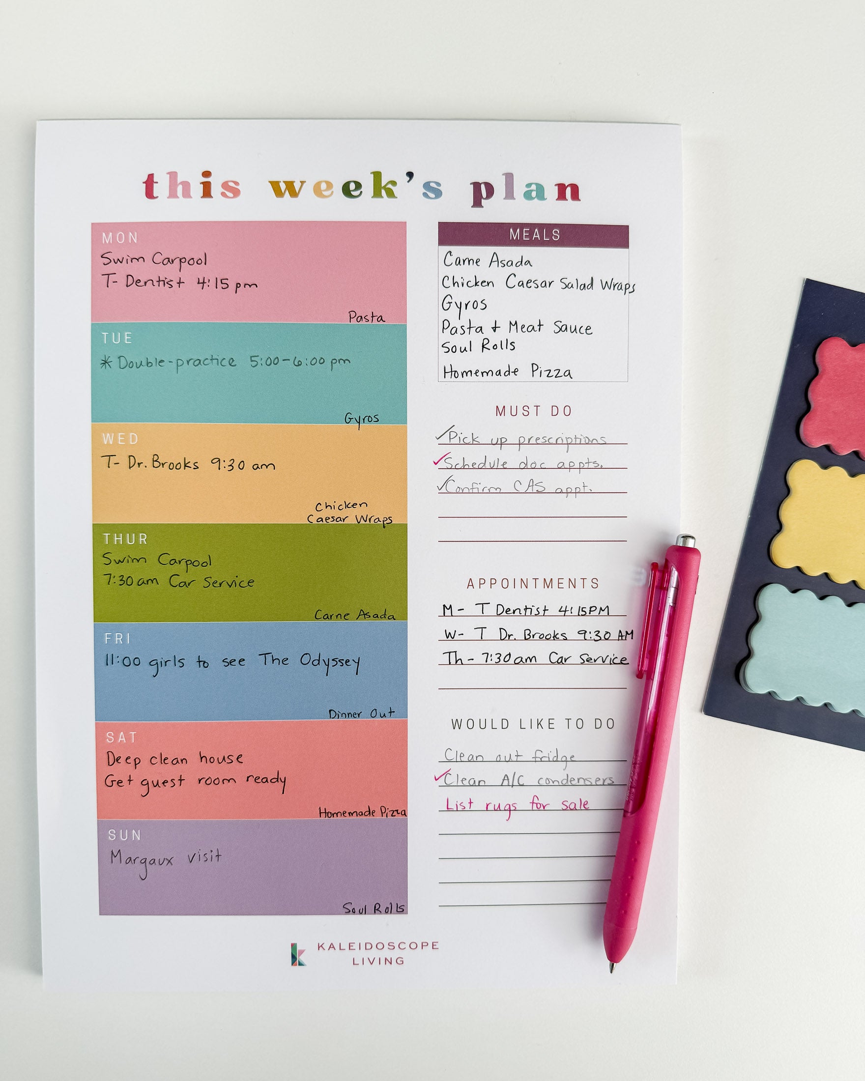 A weekly planner page from Kaleidoscope Living filled in with meals, appointments, and to-do lists, styled on a white background with a pink pen and colorful scalloped sticky notes on the side.