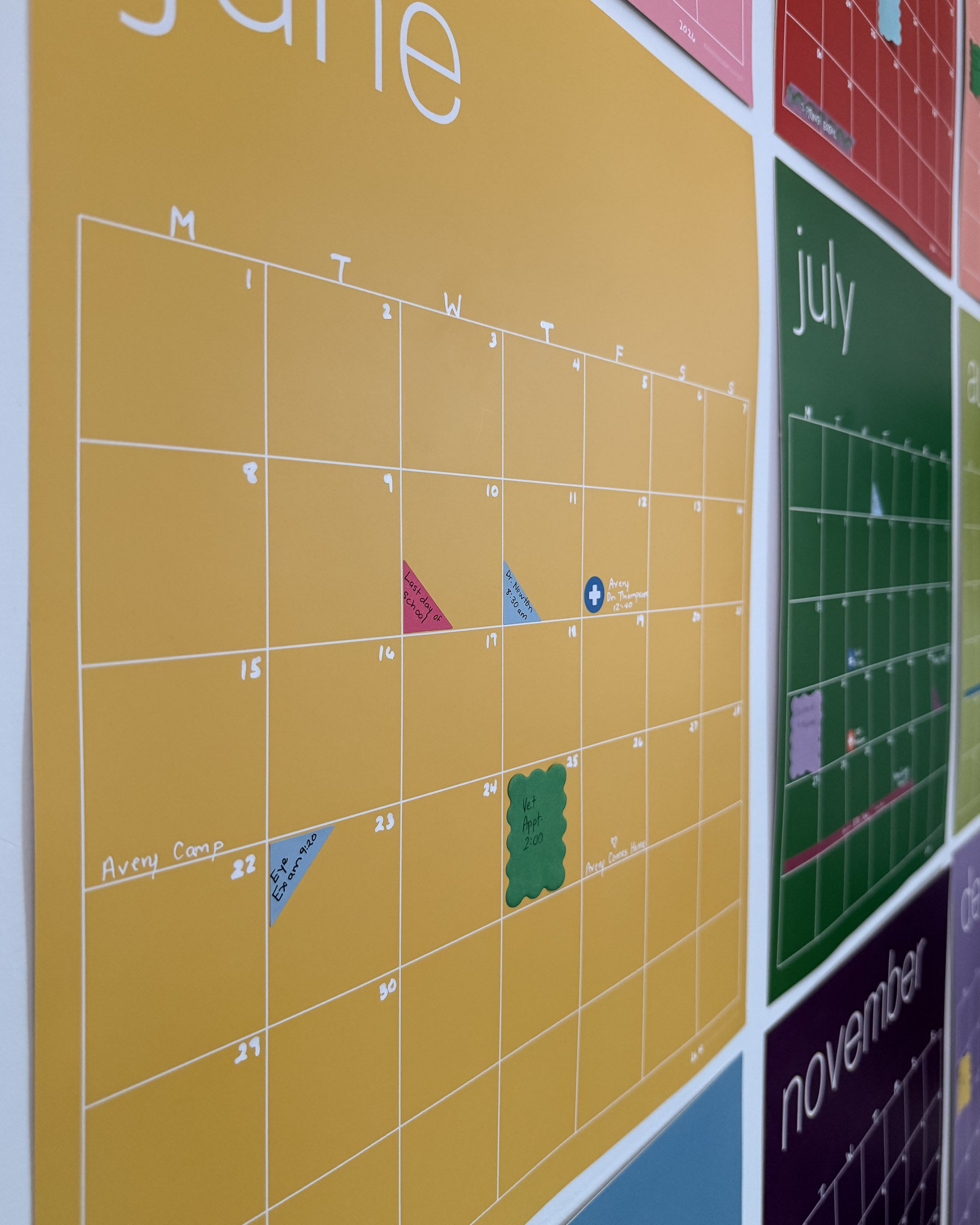 Side view of rainbow wall calendar with colorful planner and calendar stickers used to mark important appointments and events