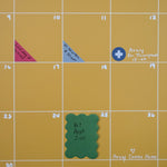 Close up view of yellow wall calendar with colorful planner and calendar stickers and scalloped sticky notes used to mark important appointments and events