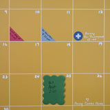 Close up view of yellow wall calendar with colorful planner and calendar stickers and scalloped sticky notes used to mark important appointments and events