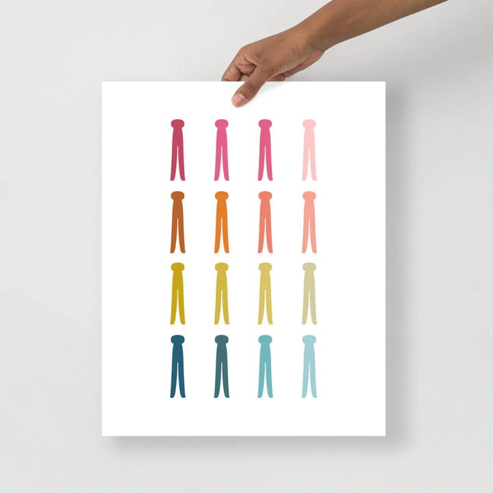 laundry room art print with a white background and grid of colorful clip art of clothes pins in ombre rainbow colors ranging from pinks to blues