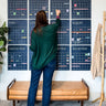 woman adding details to large reusable wall calendar in navy blue from Kaleidoscope Living