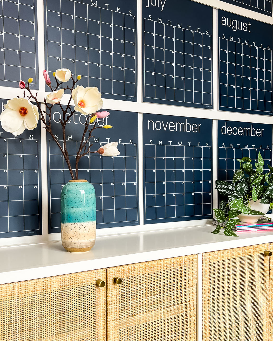 Close up of the navy reusable wall calendar from Kaleidoscope Living displayed above a piece of furniture.