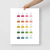office art print with a white background and grid of colorful clip art of binder clips in ombre rainbow colors ranging from pinks to blues