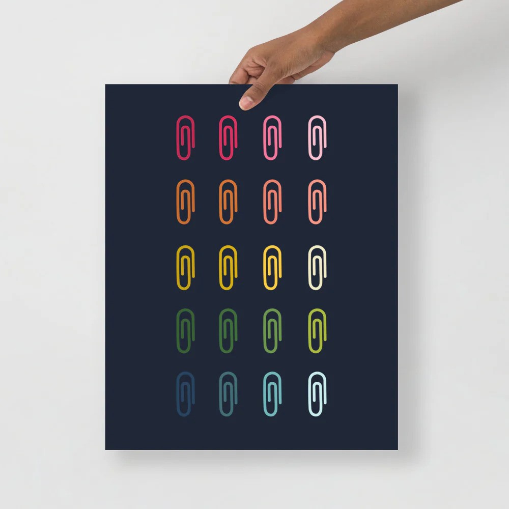 office art print with a navy background and grid of colorful clip art of paperclips in ombre rainbow colors ranging from pinks to blues