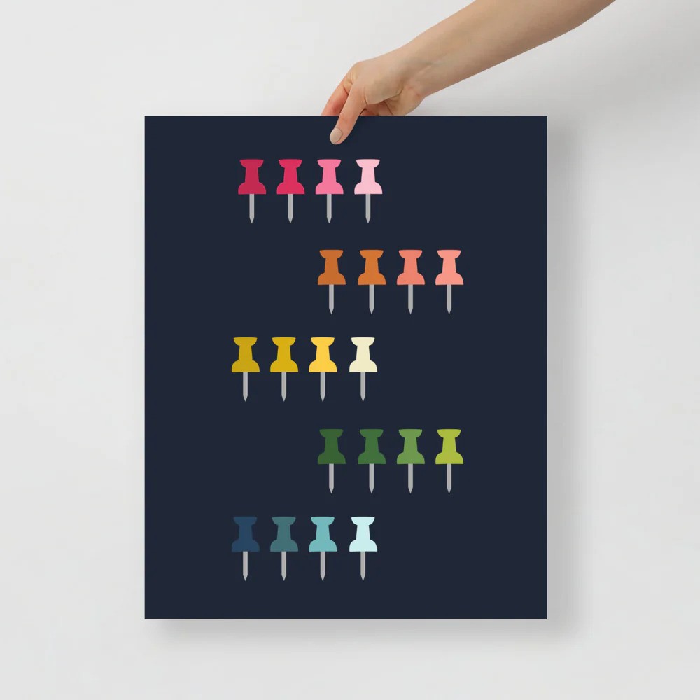 office art print with a navy background and grid of colorful clip art of push pins in ombre rainbow colors ranging from pinks to blues