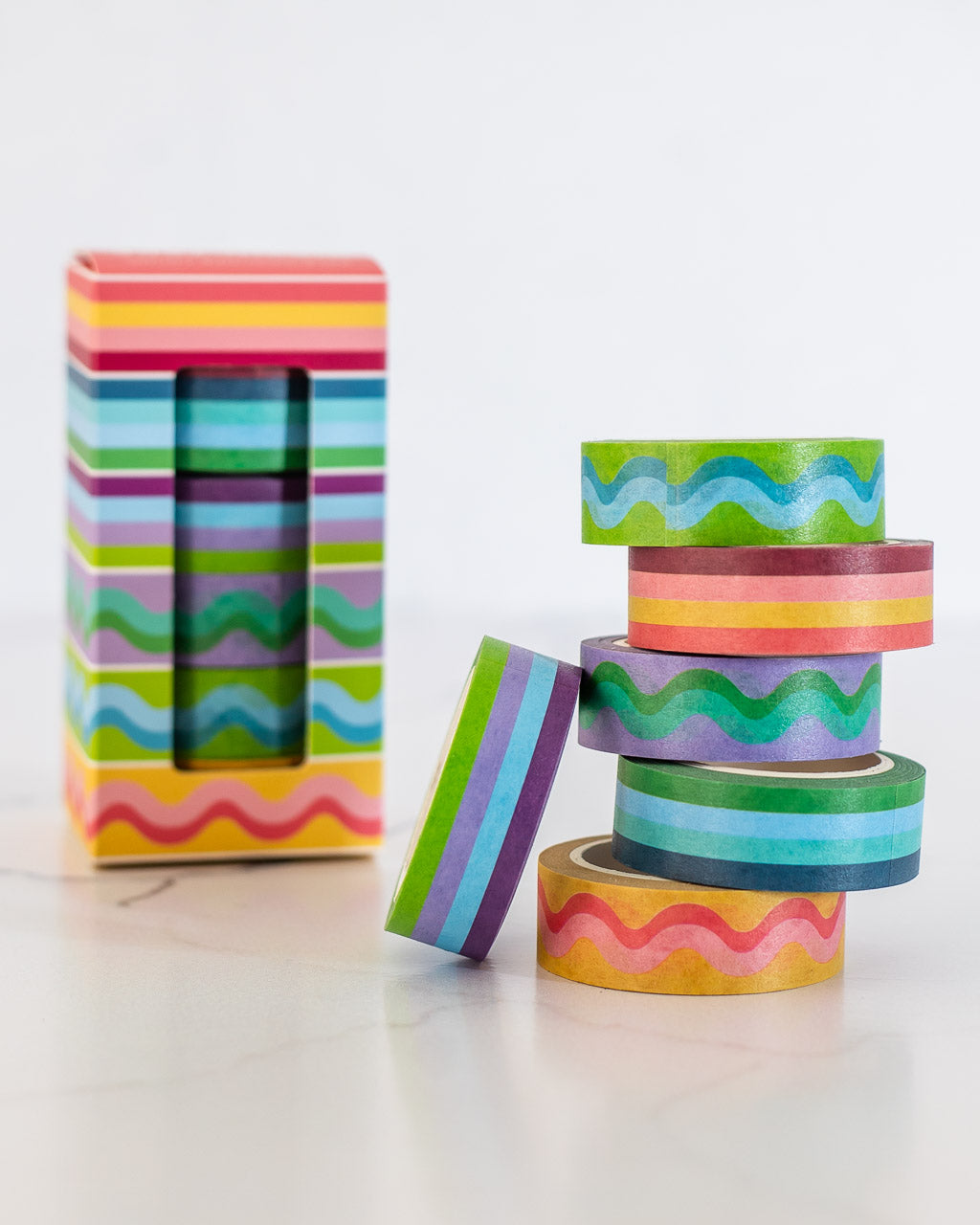 image of colorful striped and squiggle washi tape stacked in a pile with product box in background