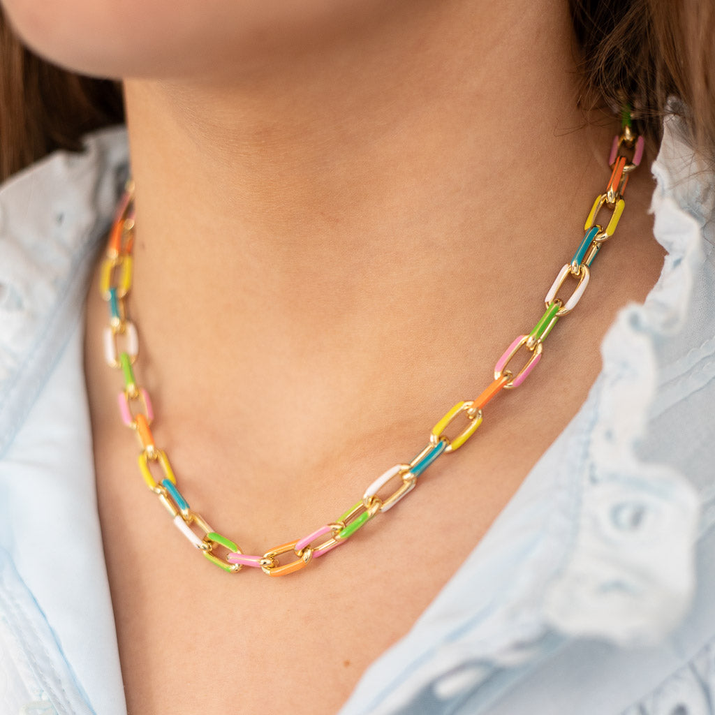 A close-up image of a person wearing a gold enamel chain necklace with multi-color accents from Kaleidoscope Living
