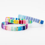 Stack of three colorful resin tile bracelets in blue, purple and rainbow hues with gold accents.