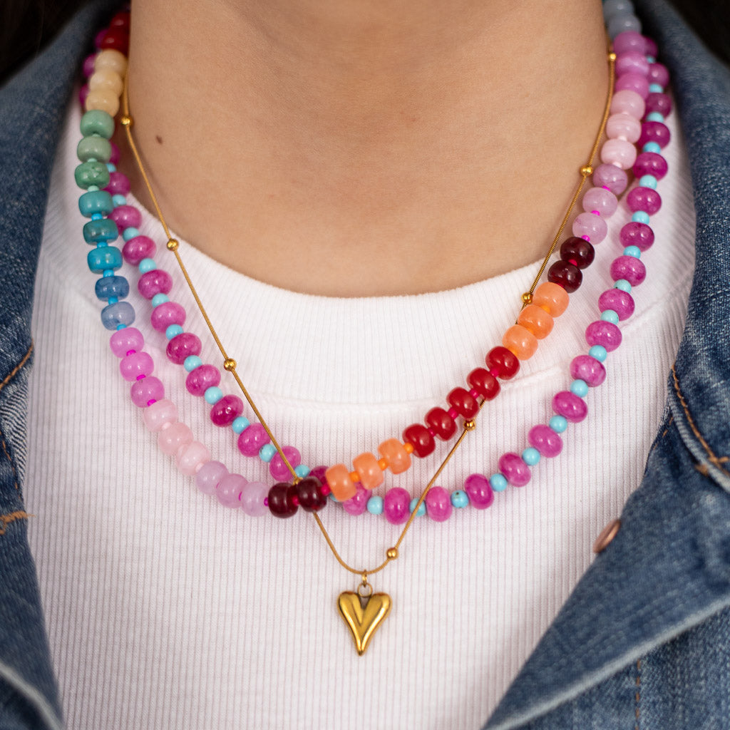 Women wearing two colorful beaded necklaces with a gold heart pendant necklace by Kaleidoscope Living