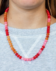 Close up of a natural stone beaded necklace in shades of red, pink and orange from Kaleidoscope Living.