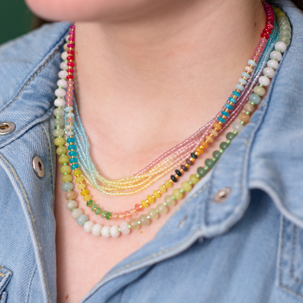 Women wearing three layers of necklaces all in subtle shades of pinks, reds, oranges, greens and blues from Kaleidoscope Living.