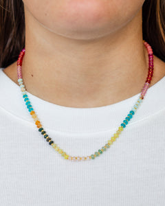 Close up of a colorful necklace with petite natural stone beads in vibrant sunset hues and gold accents.