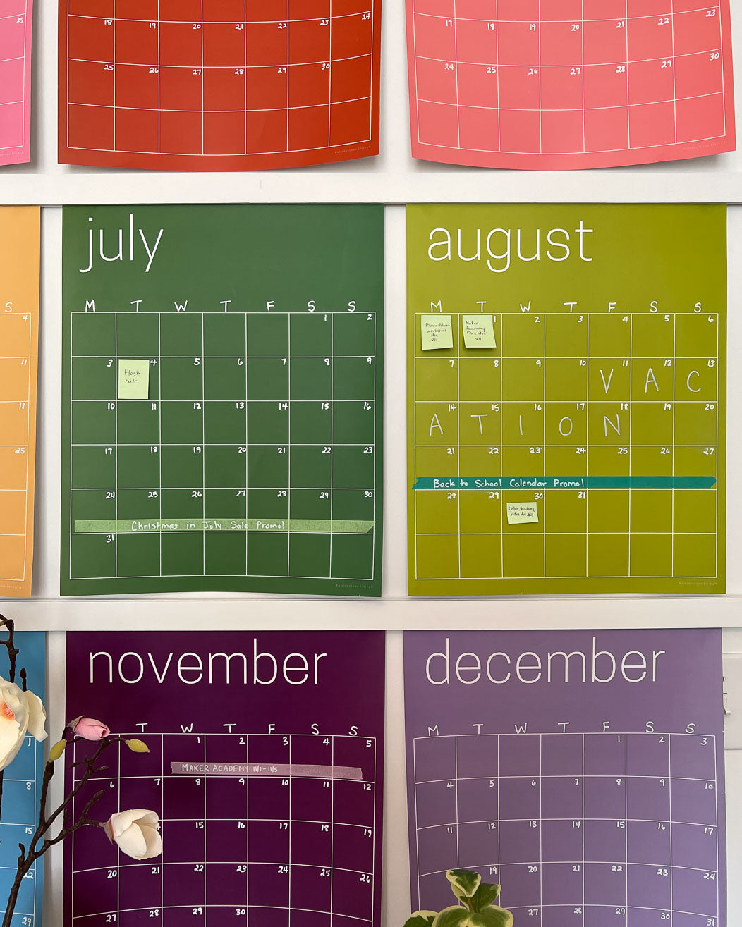 Close up of the reusable rainbow wall calendar displaying sticky notes and washi tape used on July, August and November.