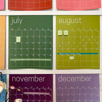 Close up of the reusable rainbow wall calendar displaying sticky notes and washi tape used on July, August and November.