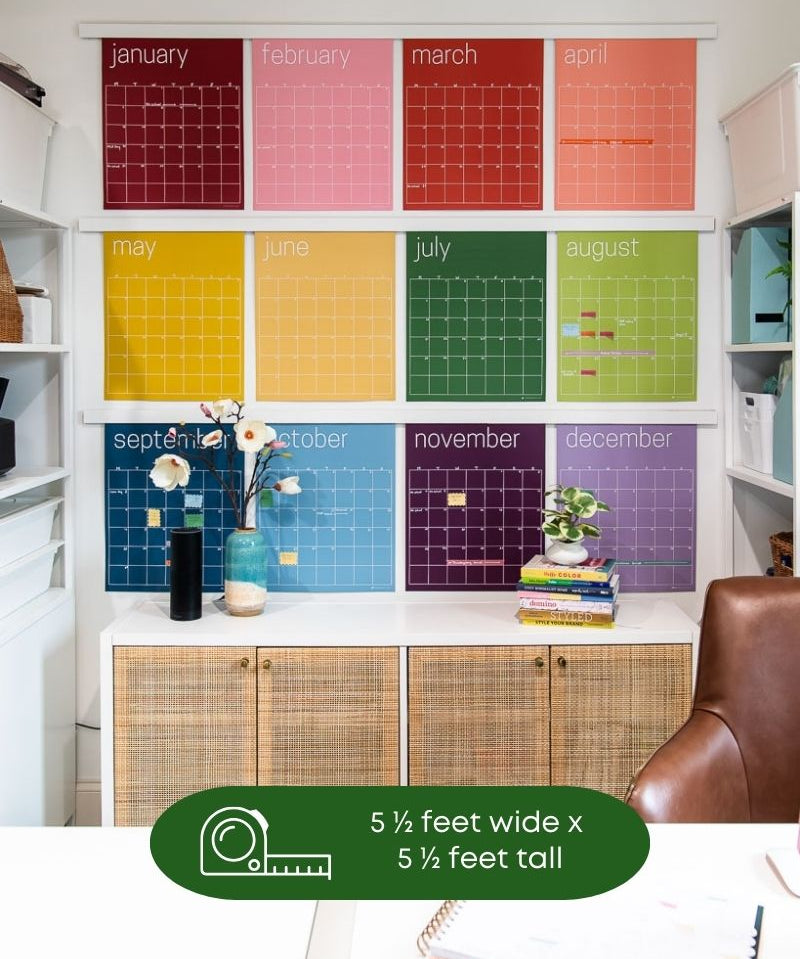 image of large reusable rainbow wall calendar hanging in home office with text overlay that showing the measurement of the wall space required for the shown hanging configuration of 5 1/2 feet wide by 5 1/2 feet tall