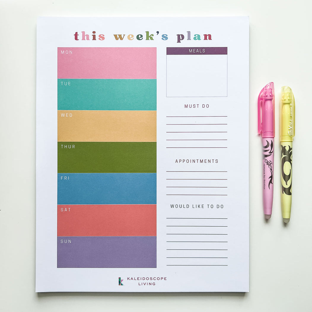 A colorful weekly planner notepad with colorful blocks for each week day plus meal planning, must do's, appointments and would like to do sections.