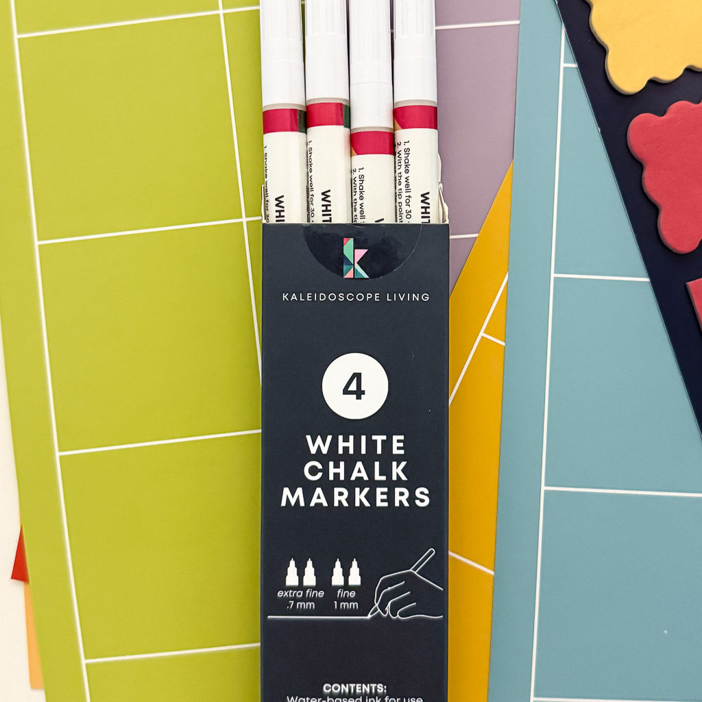 A pack of four fine-tip white liquid chalk markers, displayed in a navy blue product box that includes product information.